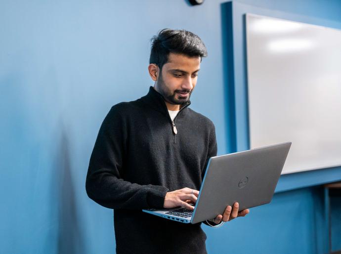 Student standing up using a laptop
