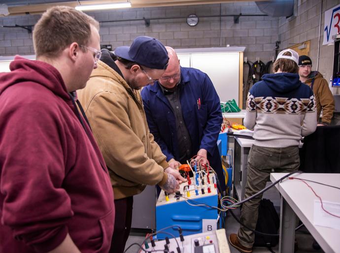 Students gathered around apparatus in the electrical lab.