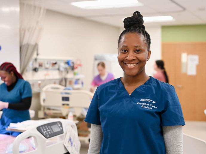 A happy practical nursing student standing in the simulation lab