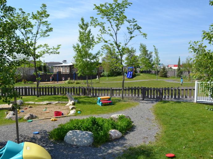 A sunny grassy area featuring a colorful playground with swings and slides, perfect for children to play and explore.