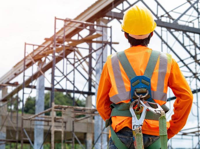 Worker wearing a hard hat and safety equipment on a job site.