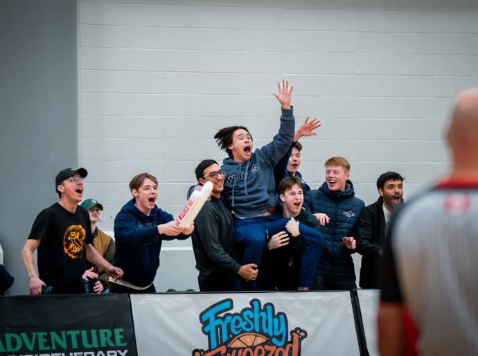 Excited fans cheer loudly for the Wolves basketball team, creating an energetic atmosphere in the Wolfden.
