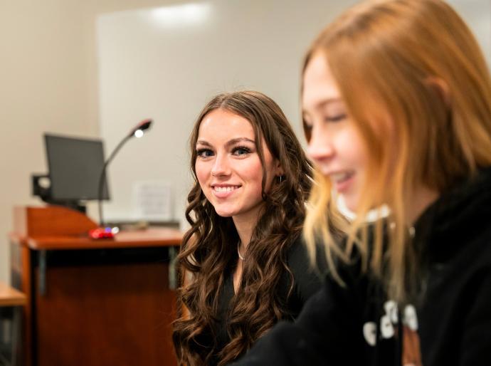 Happy student in classroom studying and smiling directly at the camera