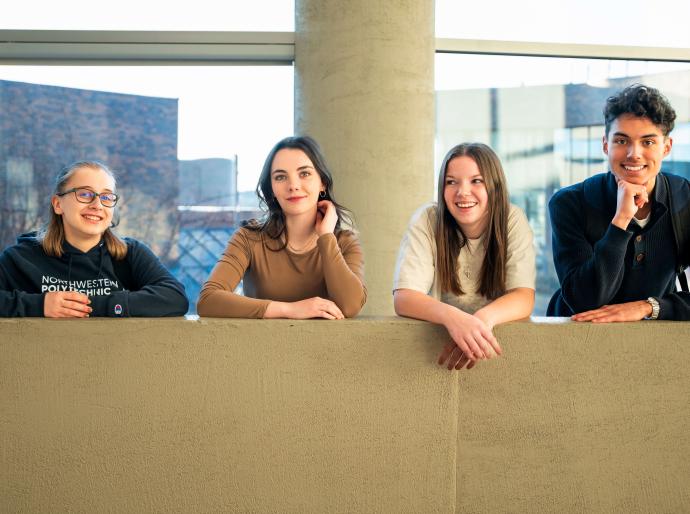 Four happy students smiling and looking at the camera