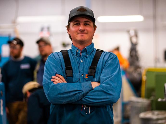 Happy trades person wearing coveralls standing in a workshop