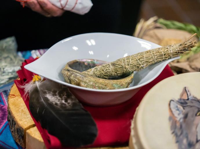 Close up of smudging stick, abalone shell, and turkey feather.