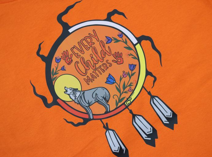 A close up of Every Child Matters artwork on an orange t-shirt