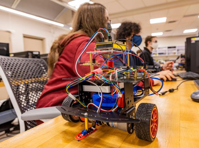 Students working on a robot with wheels in the robotics lab