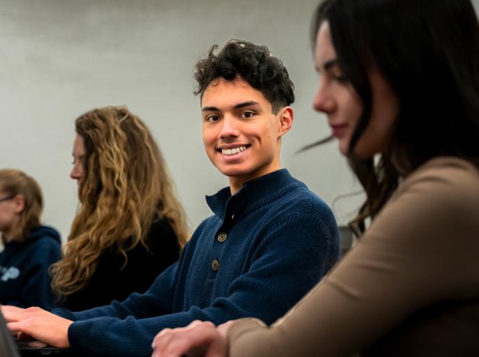 Happy student sitting in a computer lab smiling at the camera