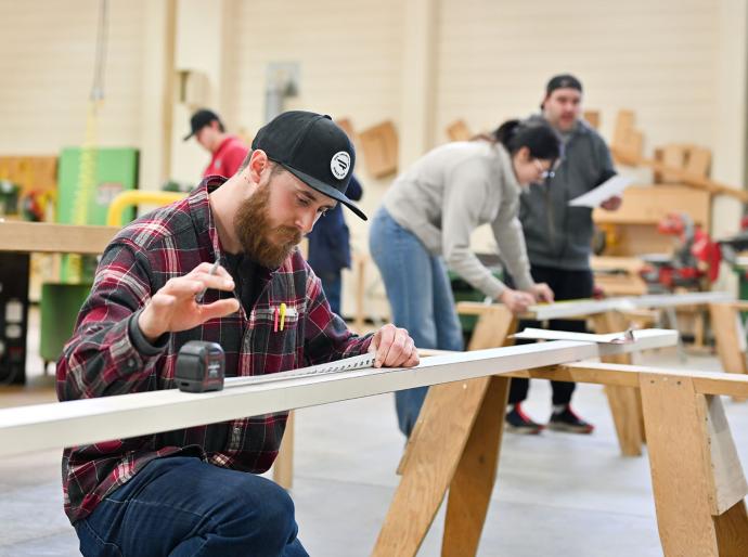 Carpentry student focused on his work in a well-equipped workshop, surrounded by tools and materials
