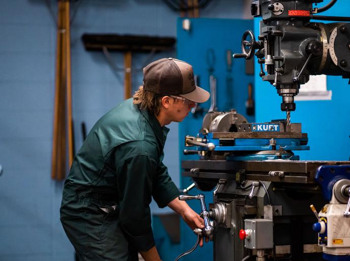 A tradesperson diligently operating a large piece of industrial equipment in a well equipped workshop.