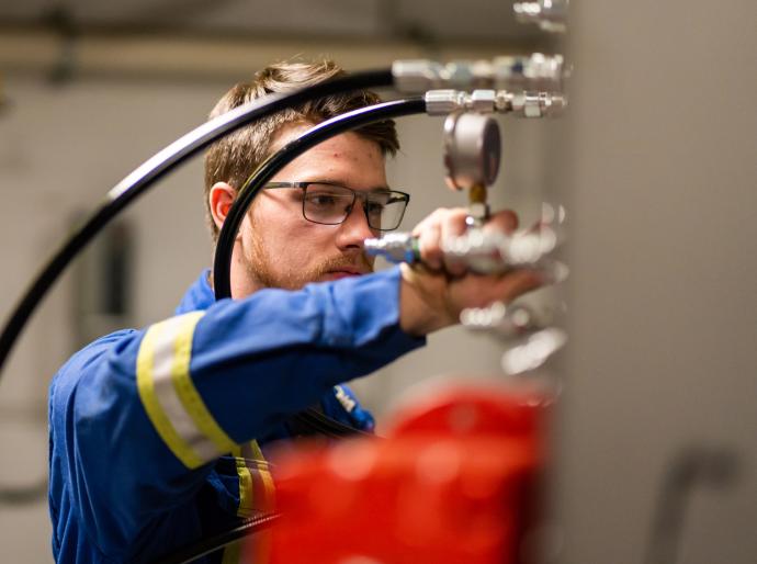 Tradesman with a wrench adjusting a pipe while looking at a gauge