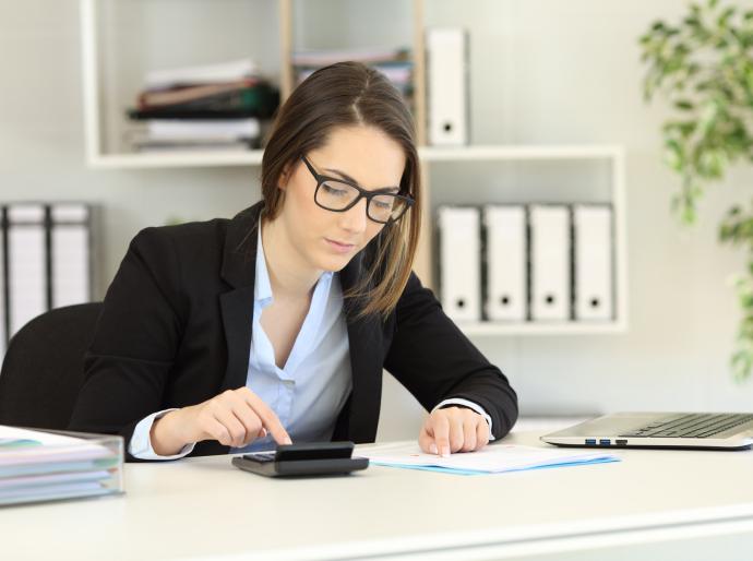 Smartly dressed professional woman focused on work in her office.