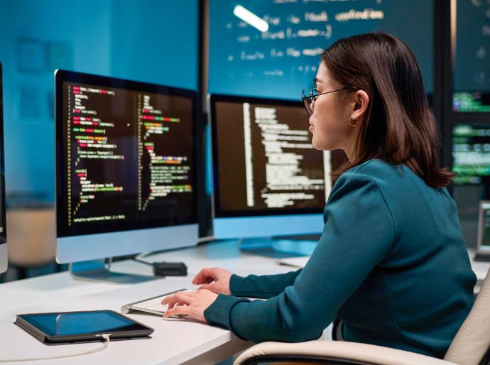 Computer programmer sitting at her desk focused on coding a program
