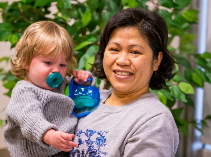 A happy early childhood educator comforting an infant.