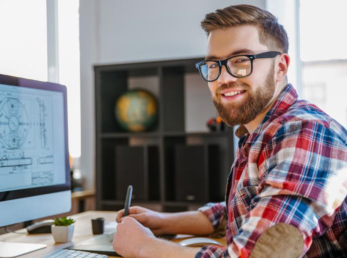 A happy engineer sitting at his computer reviewing blueprints