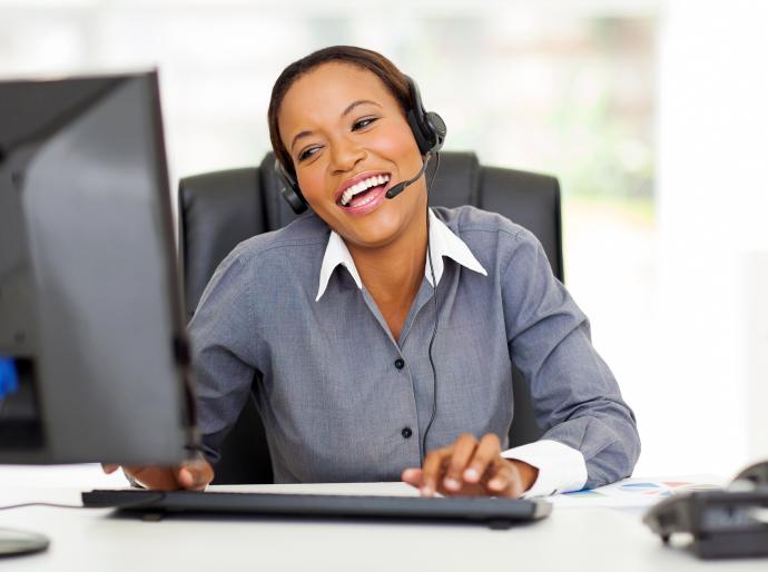 Professionally dressed woman with a headset engaging in customer service with a smile