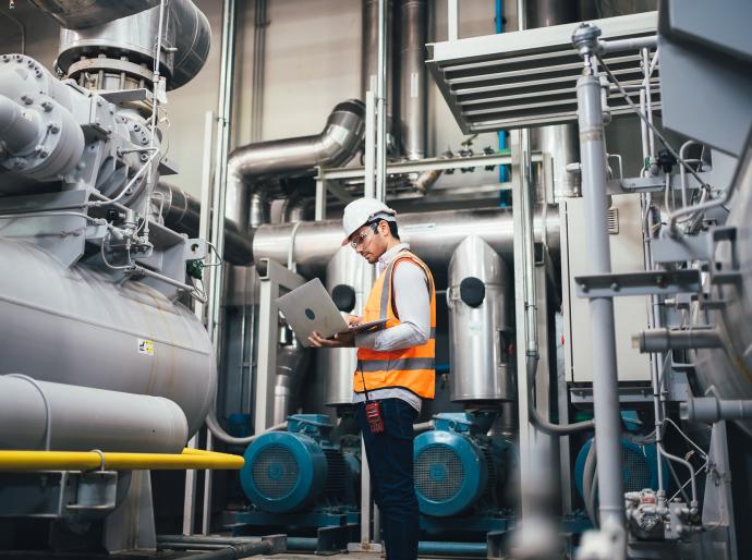 A employee in a power plant holding a clipboard and taking readings