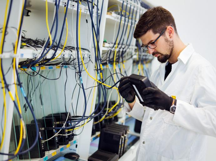 An IT support technician repairing a piece of hardware in the server room of a large company.