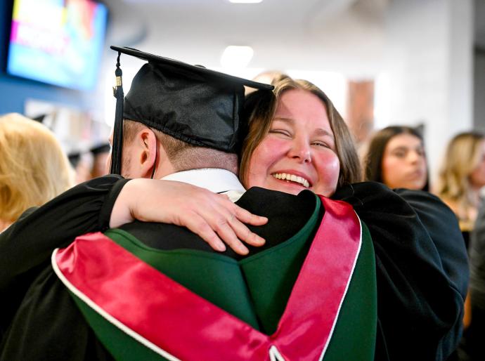 A graduate receiving a hug from a happy family member