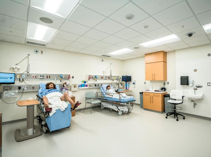 The simulation lab featuring two beds with dummies, one with a pregnant woman and the other a young child