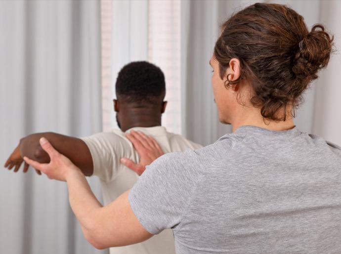 A chiropractor treating a patient by holding up the arm and extending at the elbow