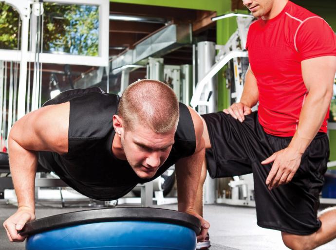 A fitness professional observing and guiding his client performing a push up
