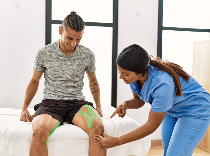 A physiotherapist examining a patients taped up knee 