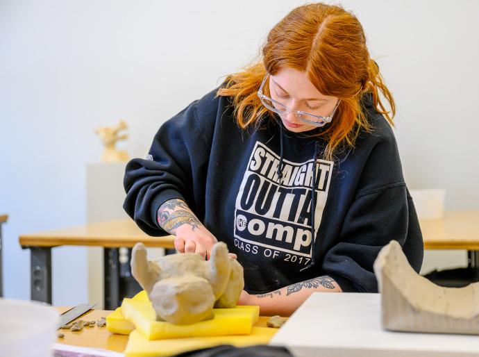 Fine arts student working on a sculpture of clay