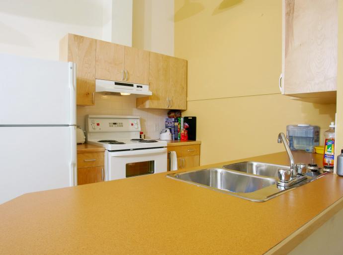 The inside of a housing unit at Fairview featuring a fridge, stove and counterspace