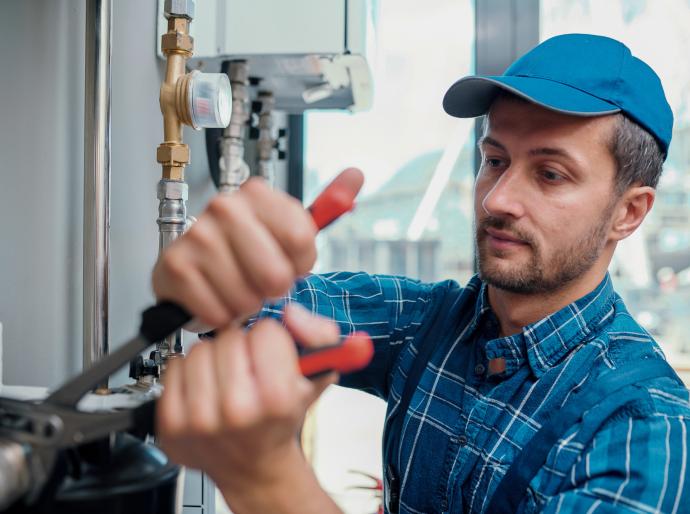 Pipefitter with a wrench performing maintenance on a piping system 