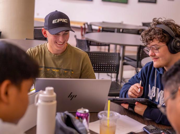 A group of happy students with laptops studying together