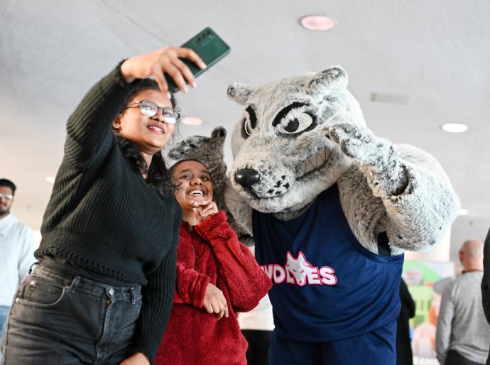 Students taking a selfie with Wolves mascot, Farley.