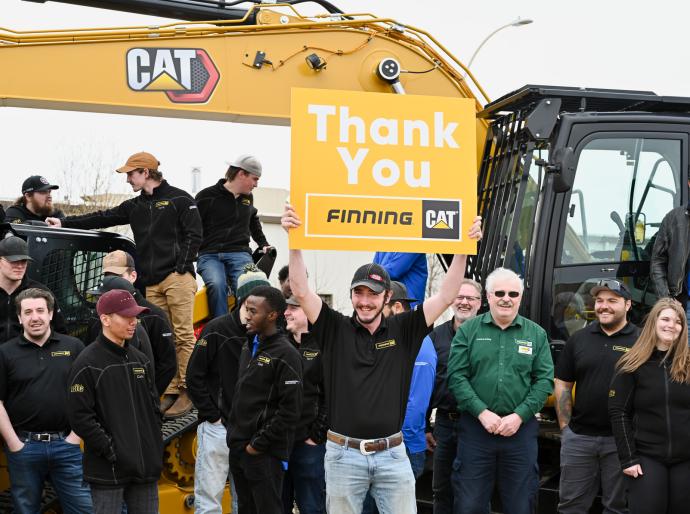 Student holding up a sign with a thank you message to Finning