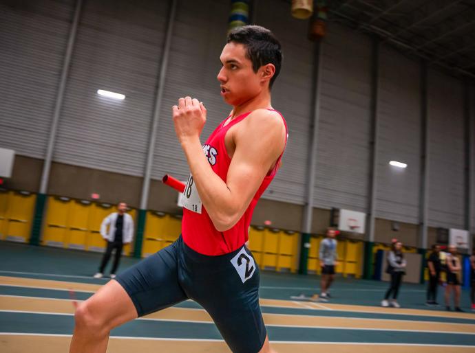 Wolves indoor track athlete sprinting in a relay
