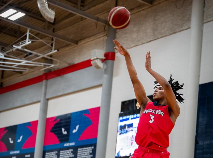 Men's wolves basketball player in the air as he is making a shot on basket