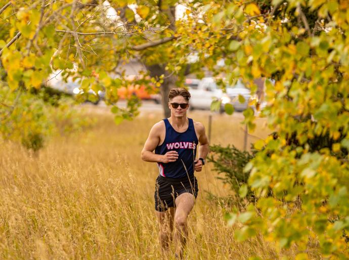 Mens x-country running running through trees and grass