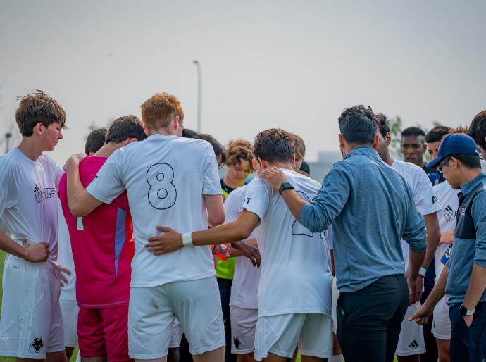 men's wolves soccer team standing in a huddle on the field during a game