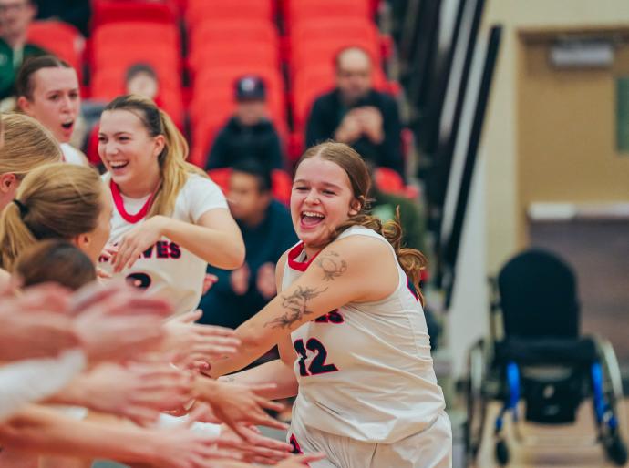 Elated womens basketball player receiving multiple high fives from her team mates