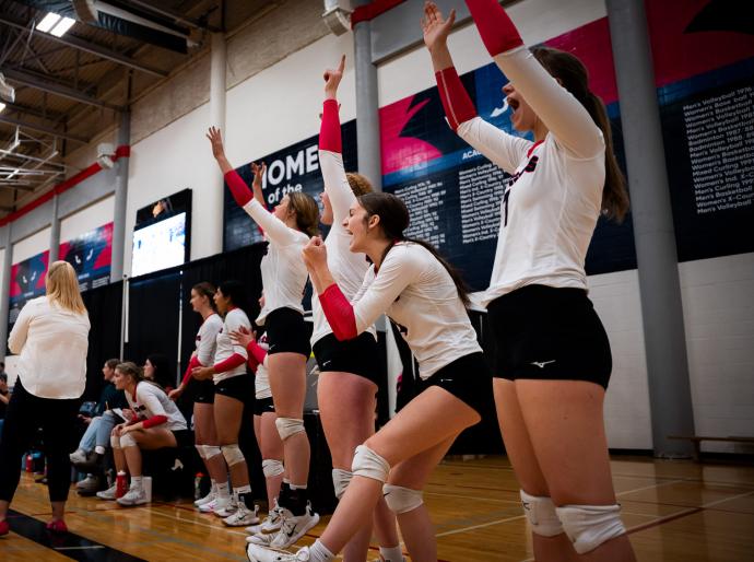 Women's volleyball players cheering from sidelines