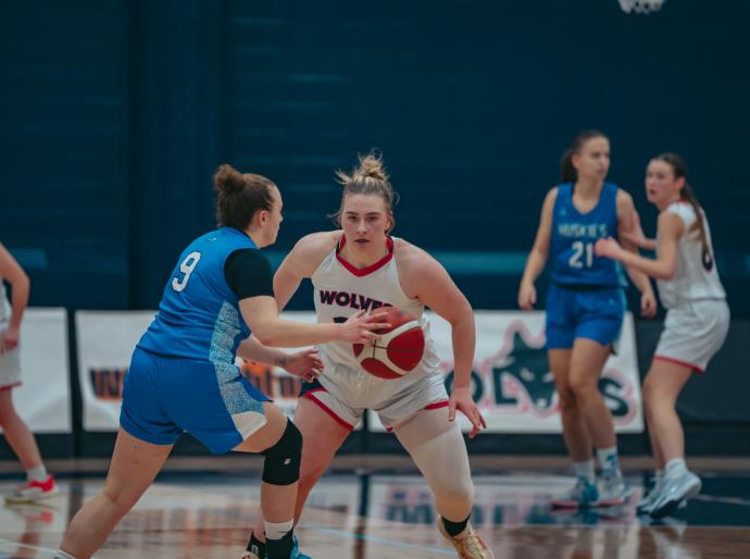 Women's wolves basketball player about to take ball from opponent on court