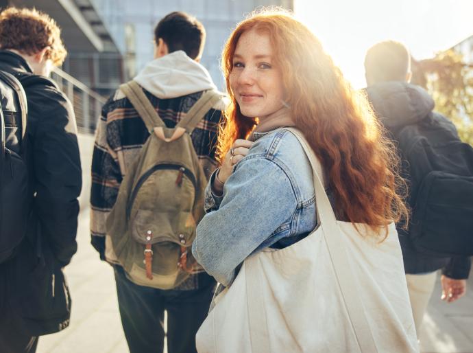 High school student looking over her shoulder as she walks towards a school