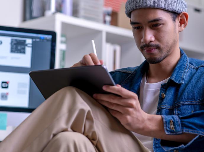 A focused graphic designer sitting and drawing on an electronic tablet