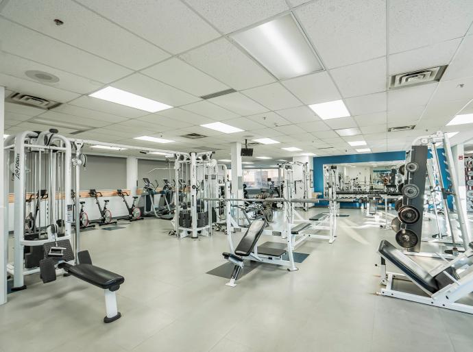 The weight room at grande prairie campus featuring weights, stationary bikes and bench press