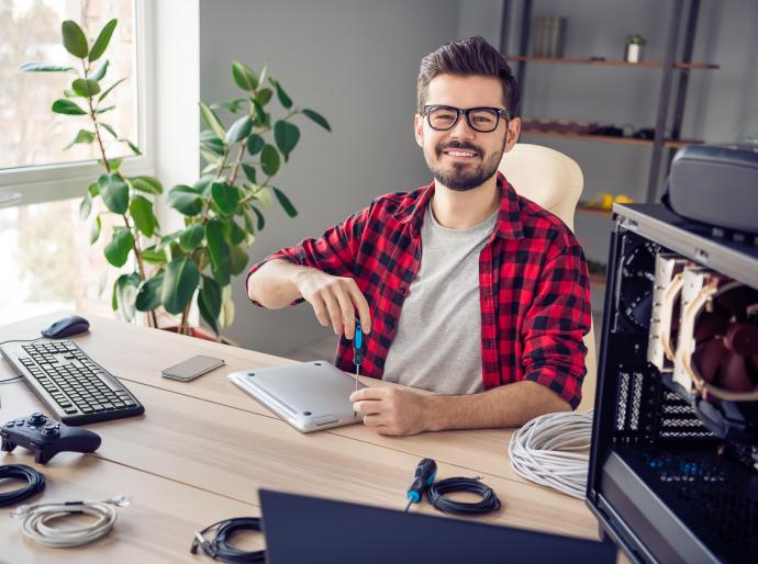 a young IT professional smiling broadly while fixing computer hardware