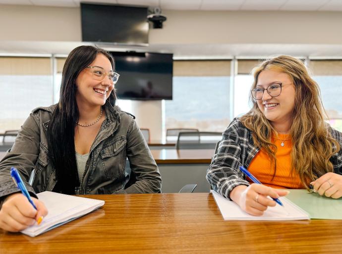 Two happy students studying in a classroom