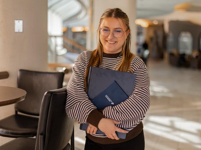 A happy student holding books on campus