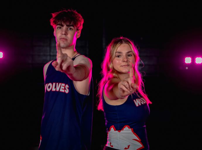 Two wolves cross country athletes holding their index fingers up