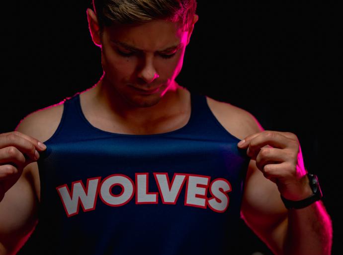 wolves cross country athlete showing the logo on the breast of his running vest