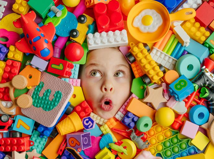 Happy child covered in colourful building blocks with only their face peeking out.